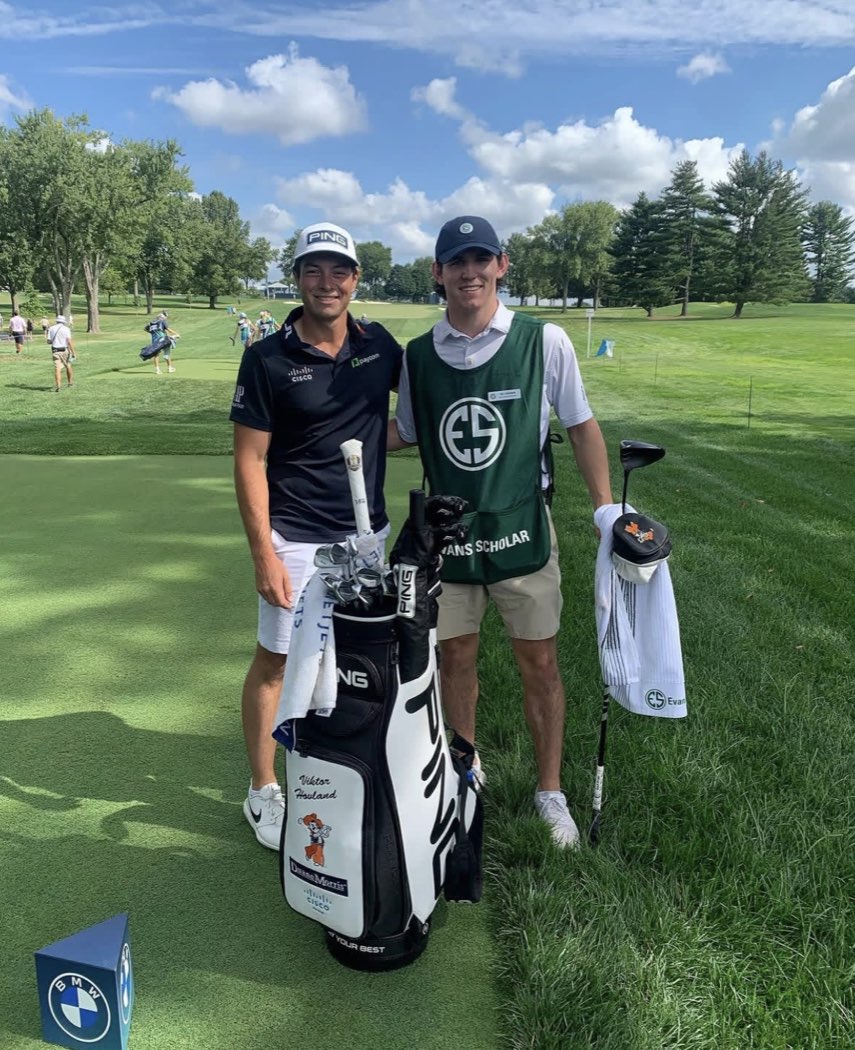 An Evans Scholar wearing an Evans Scholar caddie bib alongside a player on the fairway at a PGA TOUR event.